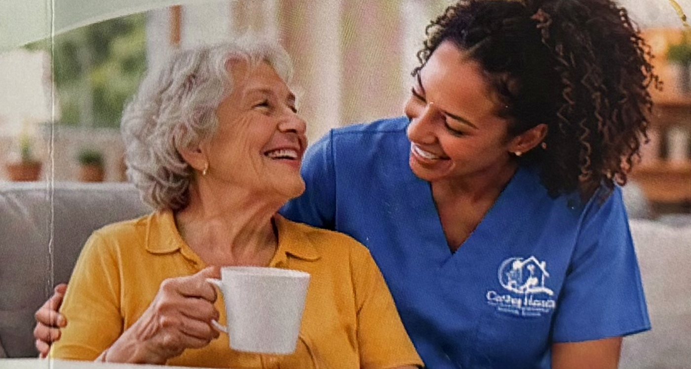 A caregiver and senior woman laughing over a cup of coffee