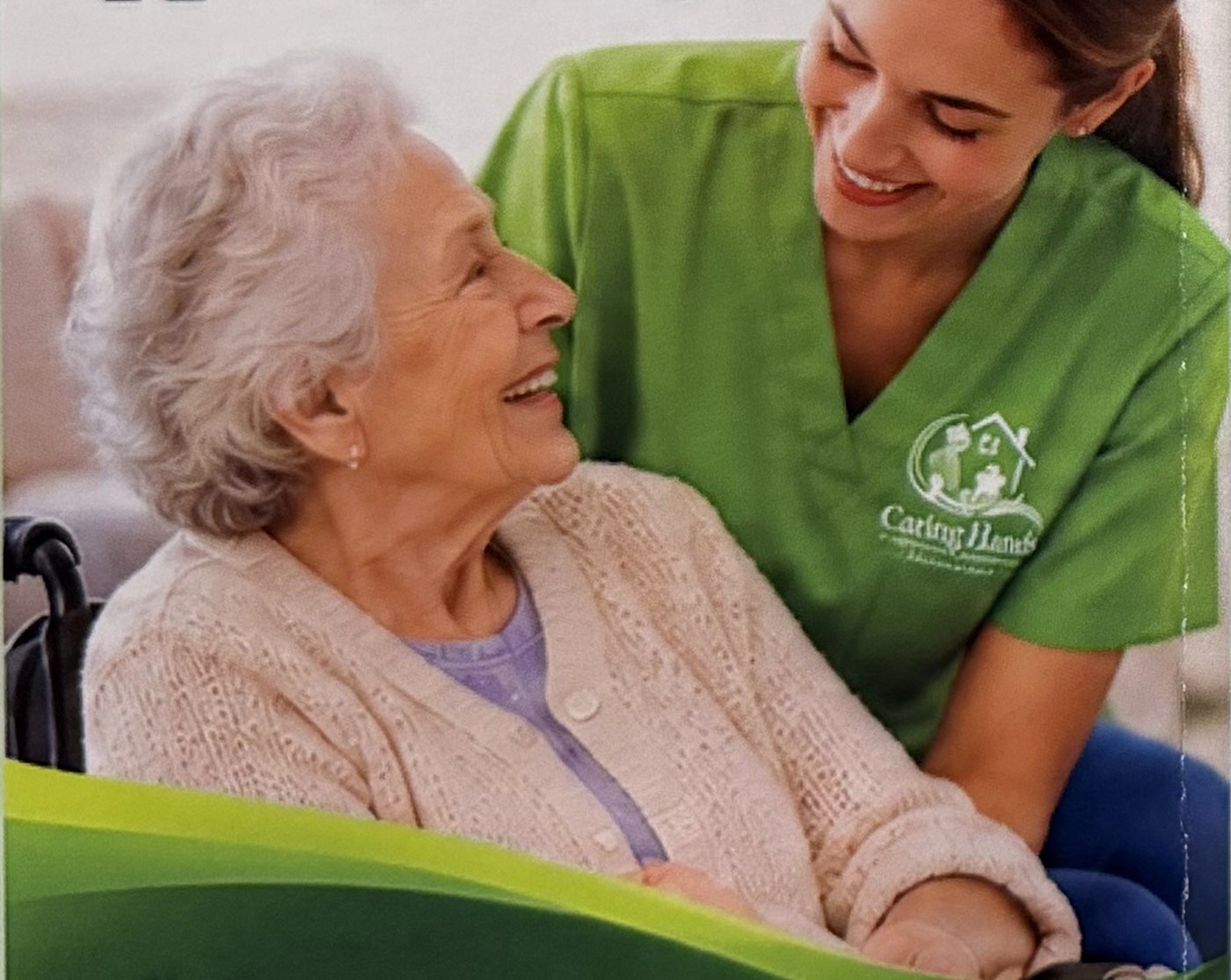 A Caring Hands caregiver in green scrubs smiling with a senior woman